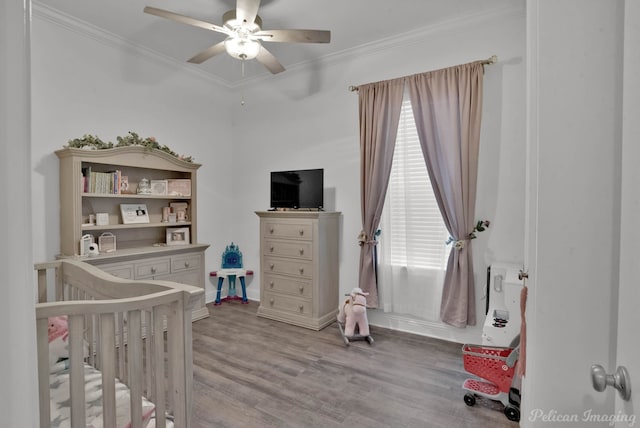 bedroom with ceiling fan, ornamental molding, a crib, and light wood-type flooring