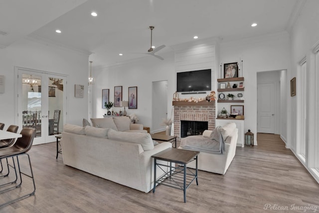 living room featuring french doors, ornamental molding, a fireplace, and light hardwood / wood-style flooring