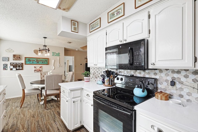 kitchen with white cabinets, decorative light fixtures, and black appliances