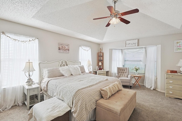 bedroom with a tray ceiling, multiple windows, ceiling fan, and carpet