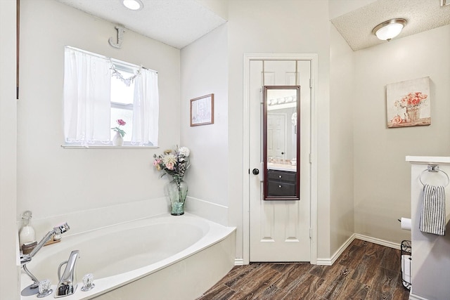 bathroom featuring a washtub, hardwood / wood-style floors, a textured ceiling, and vanity