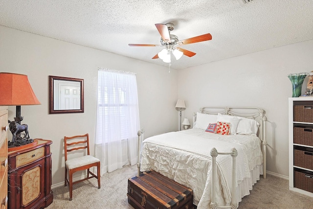 carpeted bedroom featuring ceiling fan and a textured ceiling