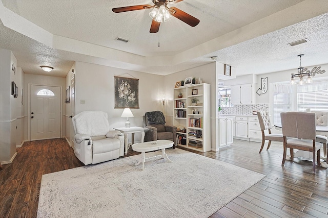 living room with a tray ceiling, ceiling fan, a textured ceiling, and dark hardwood / wood-style floors