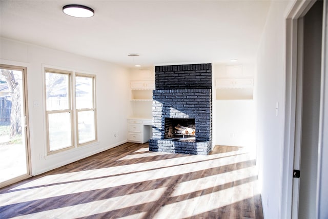 unfurnished living room featuring hardwood / wood-style floors and a brick fireplace