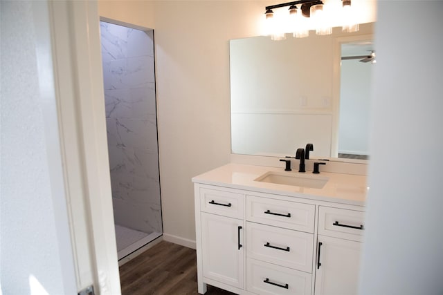 bathroom with vanity, ceiling fan, a tile shower, and wood-type flooring