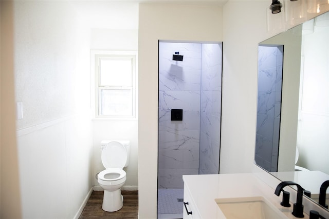 bathroom featuring tiled shower, wood-type flooring, vanity, and toilet