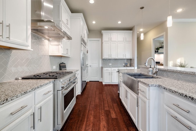 kitchen featuring high quality appliances, white cabinetry, and wall chimney range hood