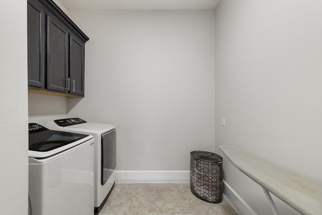 laundry room featuring light tile patterned floors, cabinets, and washing machine and clothes dryer