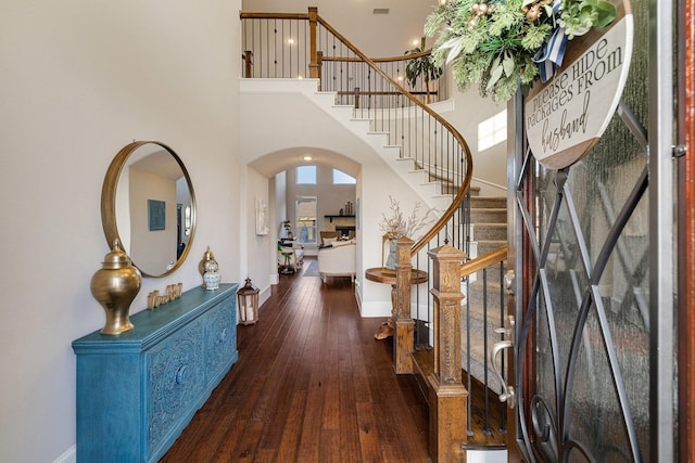 foyer entrance with a towering ceiling and dark wood-type flooring