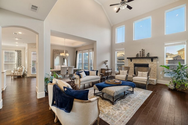 living room featuring ornamental molding, a stone fireplace, a wealth of natural light, and dark hardwood / wood-style flooring