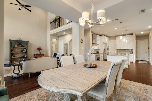 dining area with ceiling fan with notable chandelier, dark wood-type flooring, and sink