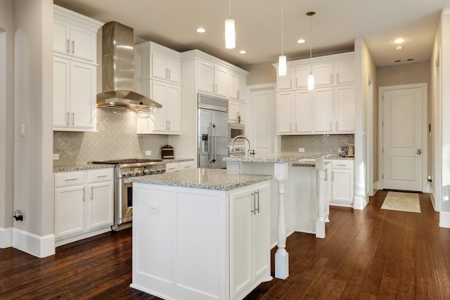 kitchen featuring white cabinetry, high end appliances, a kitchen island with sink, and wall chimney exhaust hood