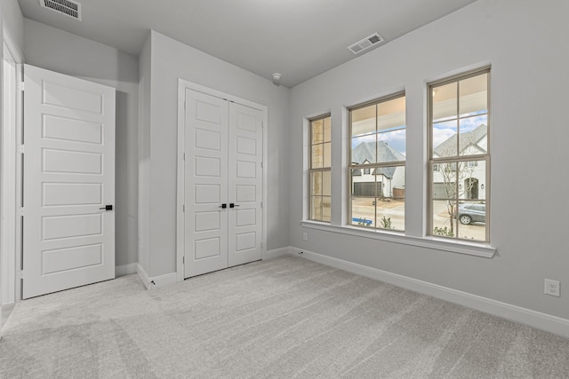 unfurnished bedroom featuring light colored carpet and a closet