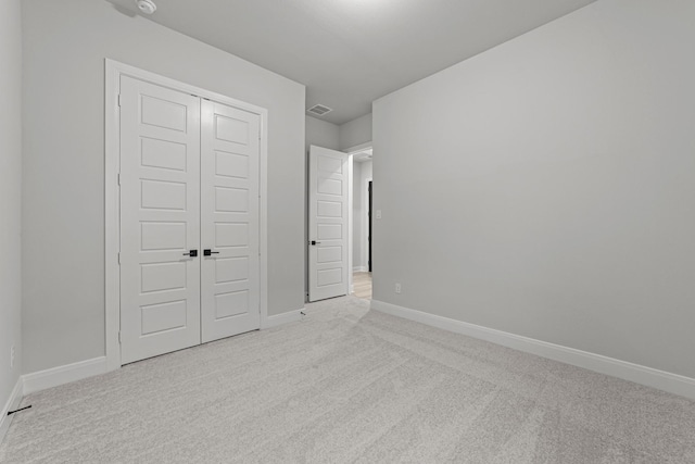 unfurnished bedroom with light colored carpet and a closet