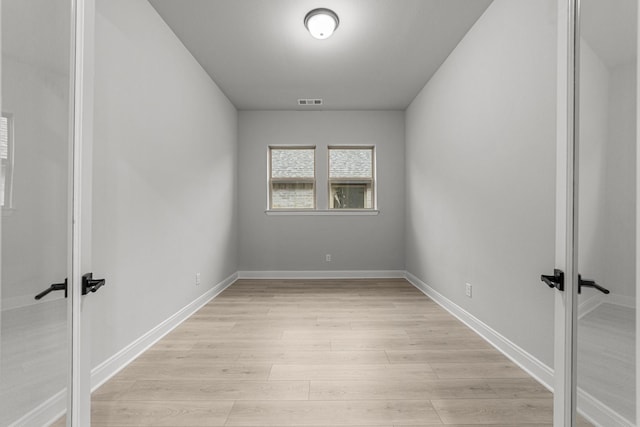 empty room with french doors and light hardwood / wood-style flooring