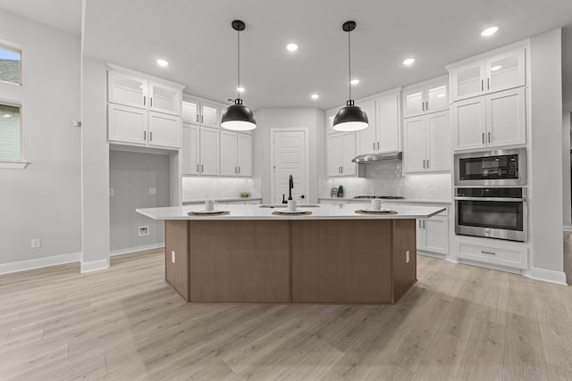 kitchen with white cabinets, an island with sink, sink, and oven