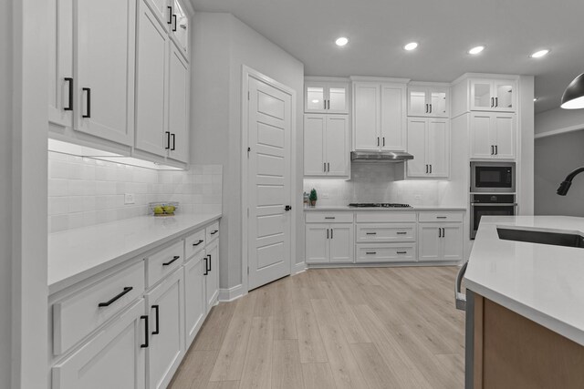 kitchen with white cabinetry, sink, black microwave, and stainless steel oven