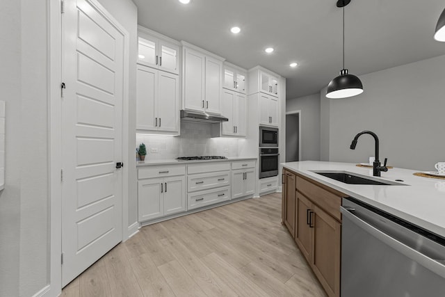 kitchen with appliances with stainless steel finishes, decorative light fixtures, sink, and white cabinets