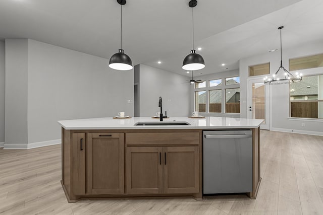 kitchen featuring sink, decorative light fixtures, dishwasher, and a center island with sink