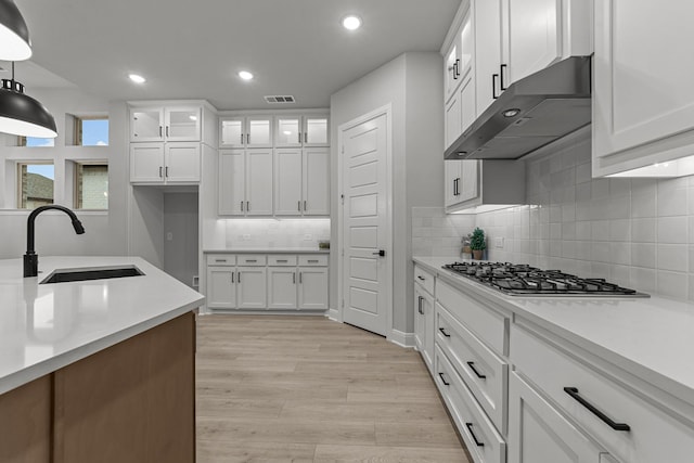 kitchen featuring white cabinetry, stainless steel gas cooktop, sink, and light hardwood / wood-style flooring