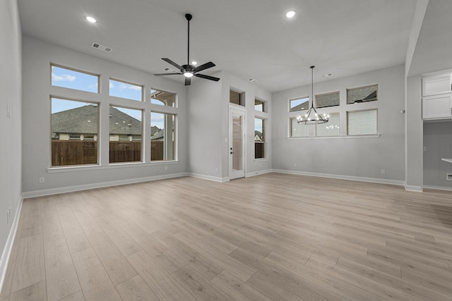 unfurnished living room featuring ceiling fan with notable chandelier and light wood-type flooring