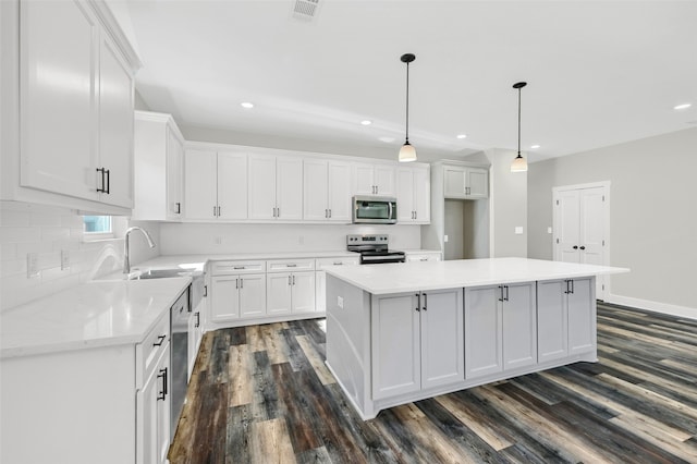 kitchen with a kitchen island, white cabinets, and appliances with stainless steel finishes