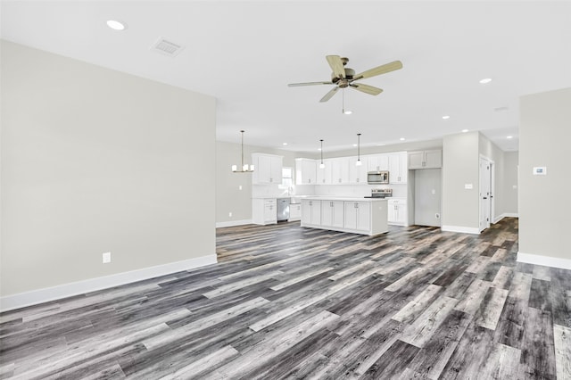 unfurnished living room with ceiling fan with notable chandelier and dark hardwood / wood-style flooring