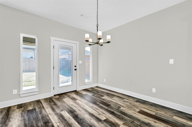 unfurnished dining area featuring an inviting chandelier and dark hardwood / wood-style flooring