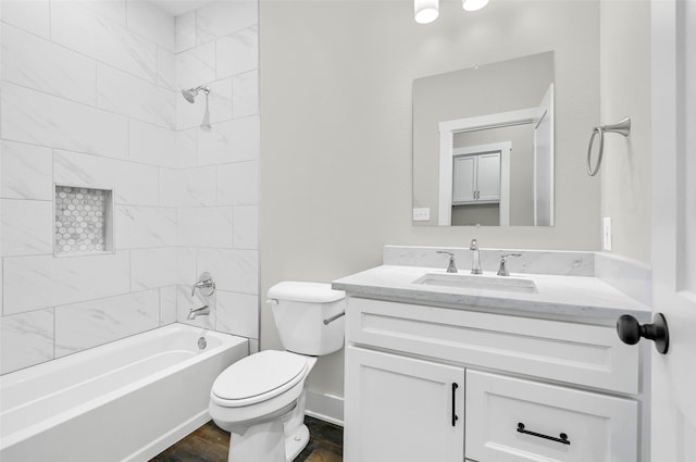 full bathroom featuring hardwood / wood-style flooring, tiled shower / bath, vanity, and toilet