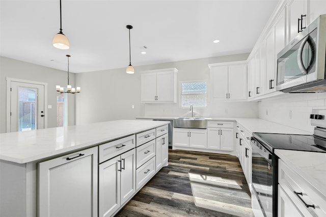 kitchen featuring pendant lighting, sink, stainless steel appliances, a center island, and white cabinets