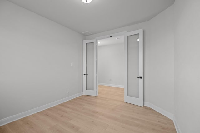 unfurnished room with baseboards, french doors, visible vents, and light wood-style floors