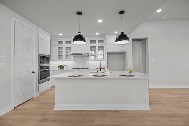 kitchen featuring light countertops, light wood-style flooring, white cabinetry, and under cabinet range hood