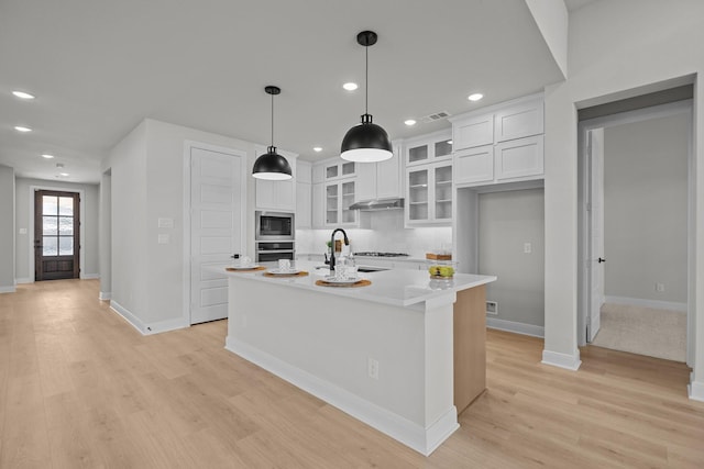 kitchen with built in microwave, white cabinetry, stainless steel oven, and a sink