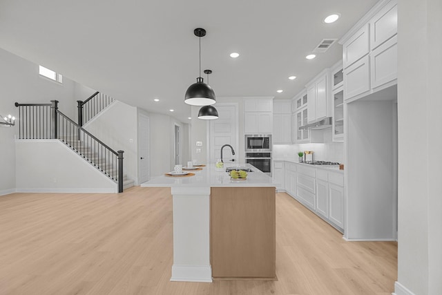 kitchen with light countertops, appliances with stainless steel finishes, a sink, and light wood-style floors