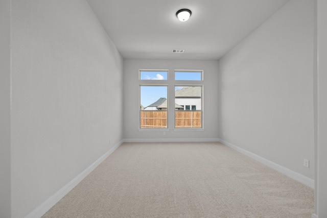 empty room with light colored carpet, visible vents, and baseboards