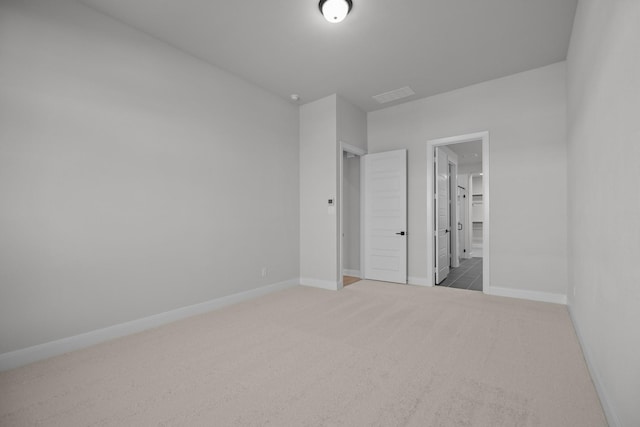 unfurnished bedroom featuring ensuite bathroom, carpet, visible vents, and baseboards