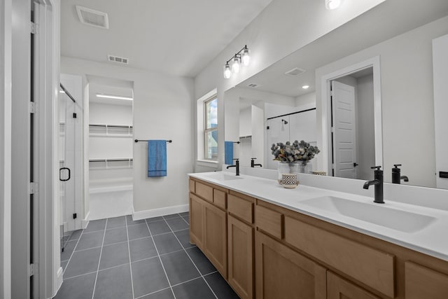 full bathroom with tile patterned flooring, a spacious closet, a sink, and a shower stall