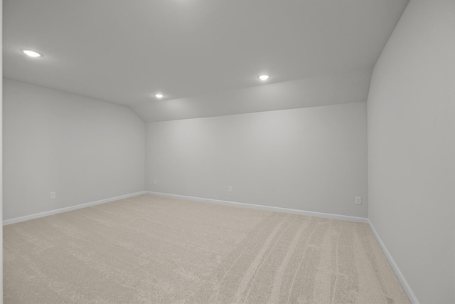 spare room with recessed lighting, light colored carpet, vaulted ceiling, and baseboards