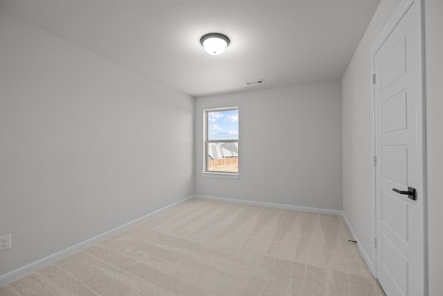 spare room featuring light carpet, visible vents, and baseboards