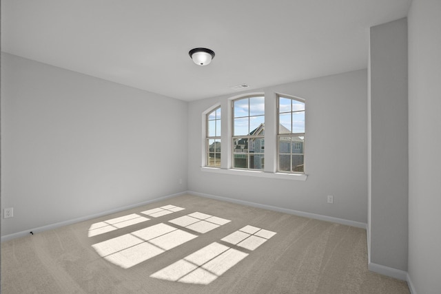 empty room featuring carpet floors, visible vents, and baseboards