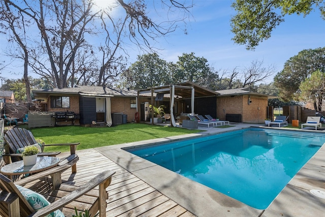 back of house featuring a fenced in pool, a pergola, and a lawn