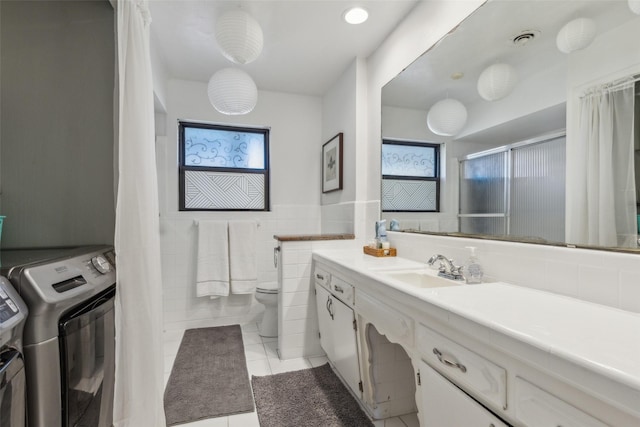 bathroom featuring tile patterned floors, vanity, washer and dryer, tile walls, and toilet