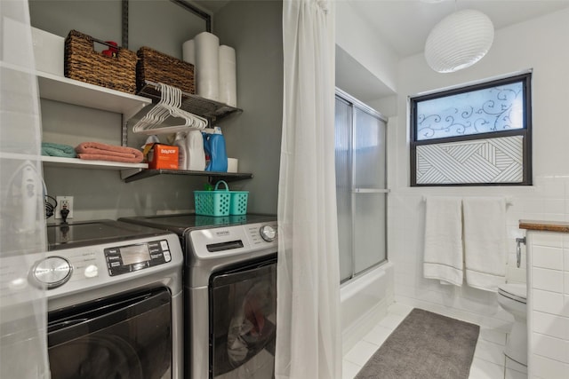 laundry room featuring light tile patterned floors, tile walls, and independent washer and dryer