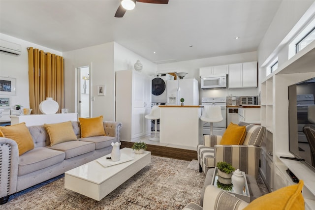 living room with a wall unit AC, ceiling fan, light hardwood / wood-style floors, and stacked washer and clothes dryer