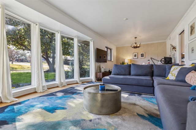 living room featuring hardwood / wood-style flooring, ornamental molding, and an inviting chandelier