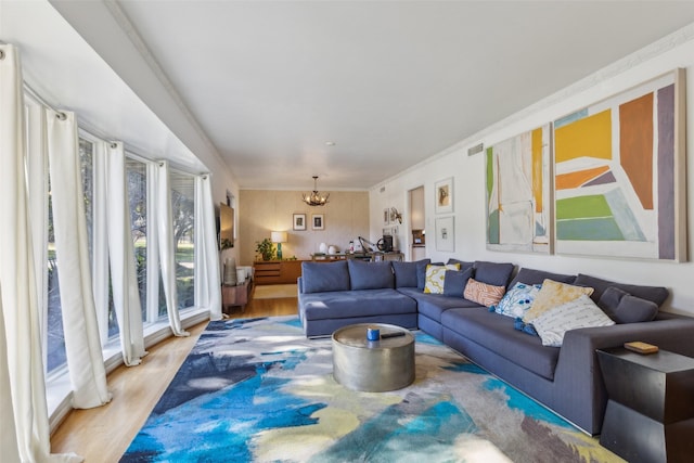 living room featuring a chandelier, light wood-type flooring, and ornamental molding