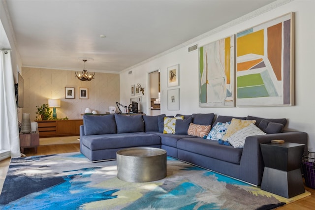 living room with hardwood / wood-style flooring, ornamental molding, and an inviting chandelier