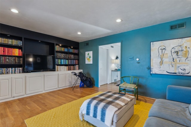 living room featuring built in shelves and light wood-type flooring