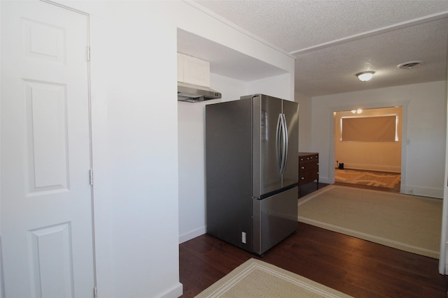 950 N Munday Ave, Munday, TX 76371 - kitchen with dark wood-type flooring, stainless steel fridge, a textured ceiling, and white cabinets