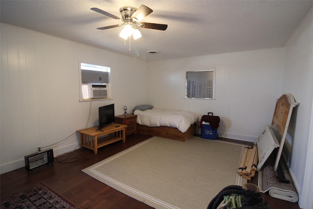 950 N Munday Ave, Munday, TX 76371 - bedroom with cooling unit, ceiling fan, dark wood-type flooring, and a textured ceiling